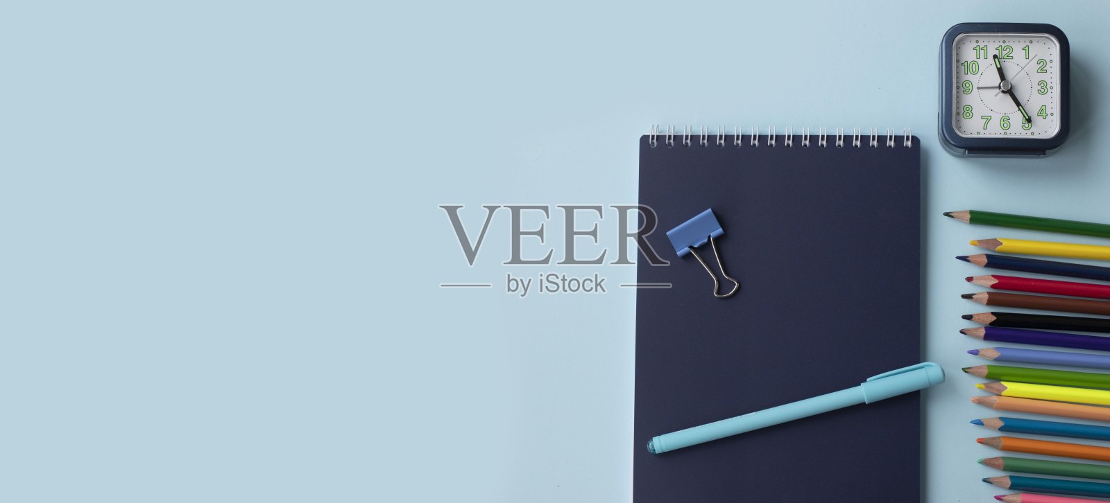 一套学校和办公用品在蓝色背景:钢笔，回别针，纸条，彩色铅笔，蜡笔，毡尖笔和闹钟。理念:回到学校。Flatlay顶视图。照片摄影图片