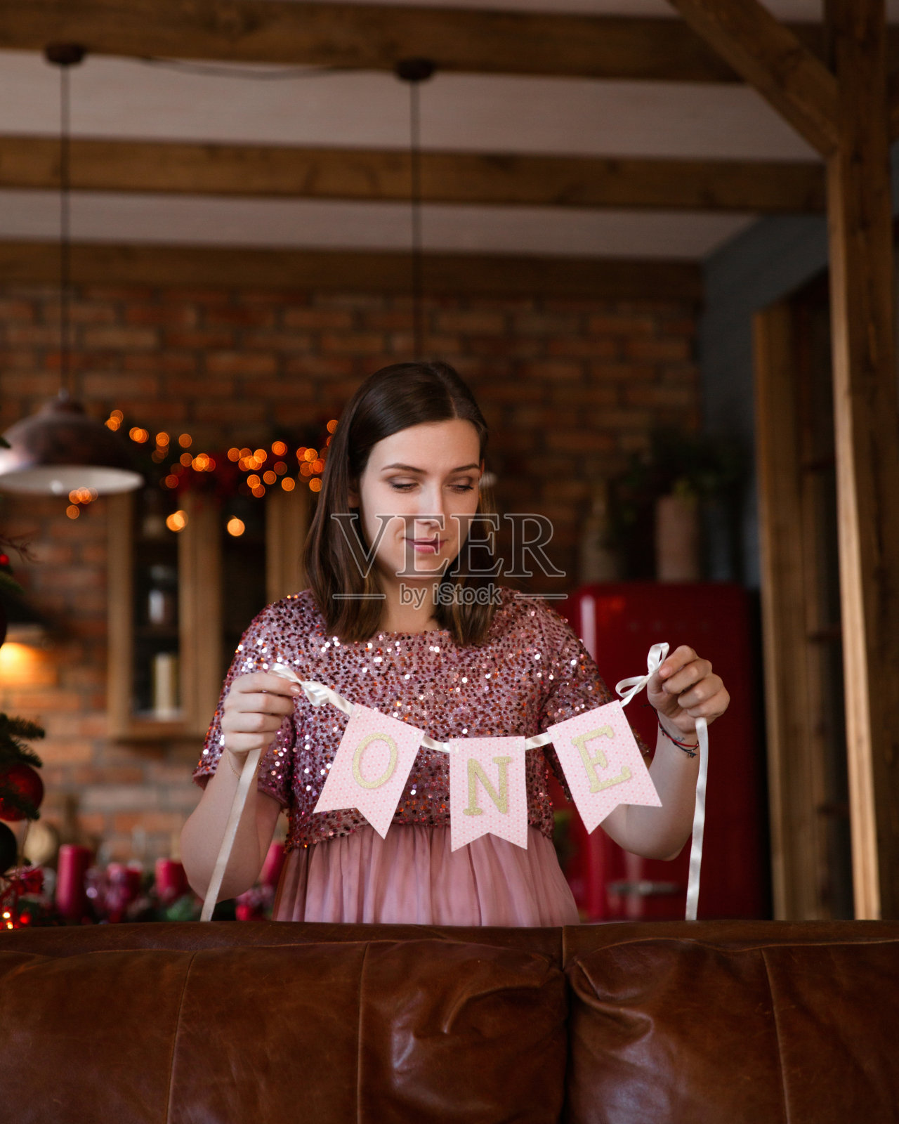 年轻女子拿着生日花环庆祝婴儿生日。照片摄影图片