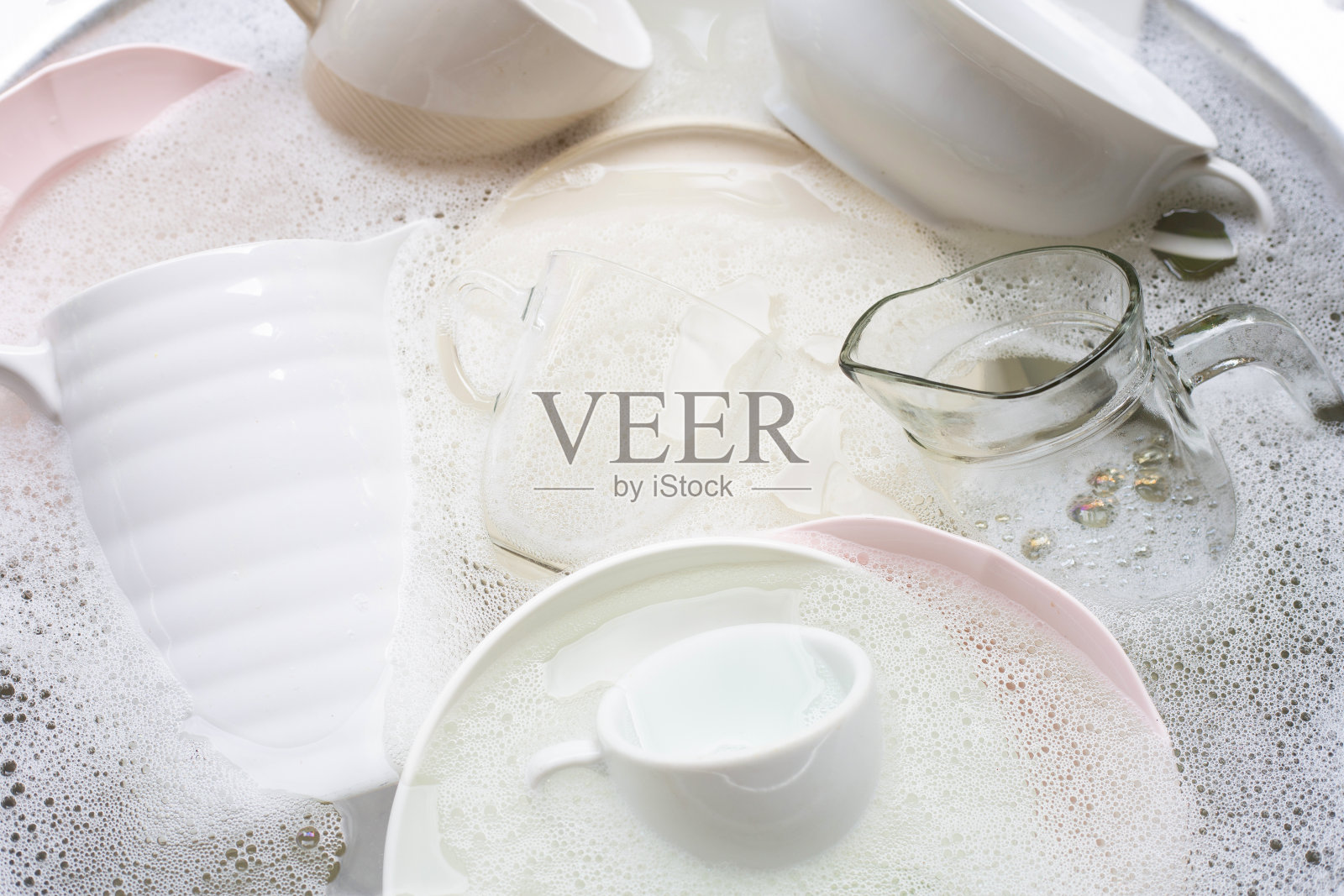 洗盘子，靠近浸泡在厨房水槽中的器具。照片摄影图片