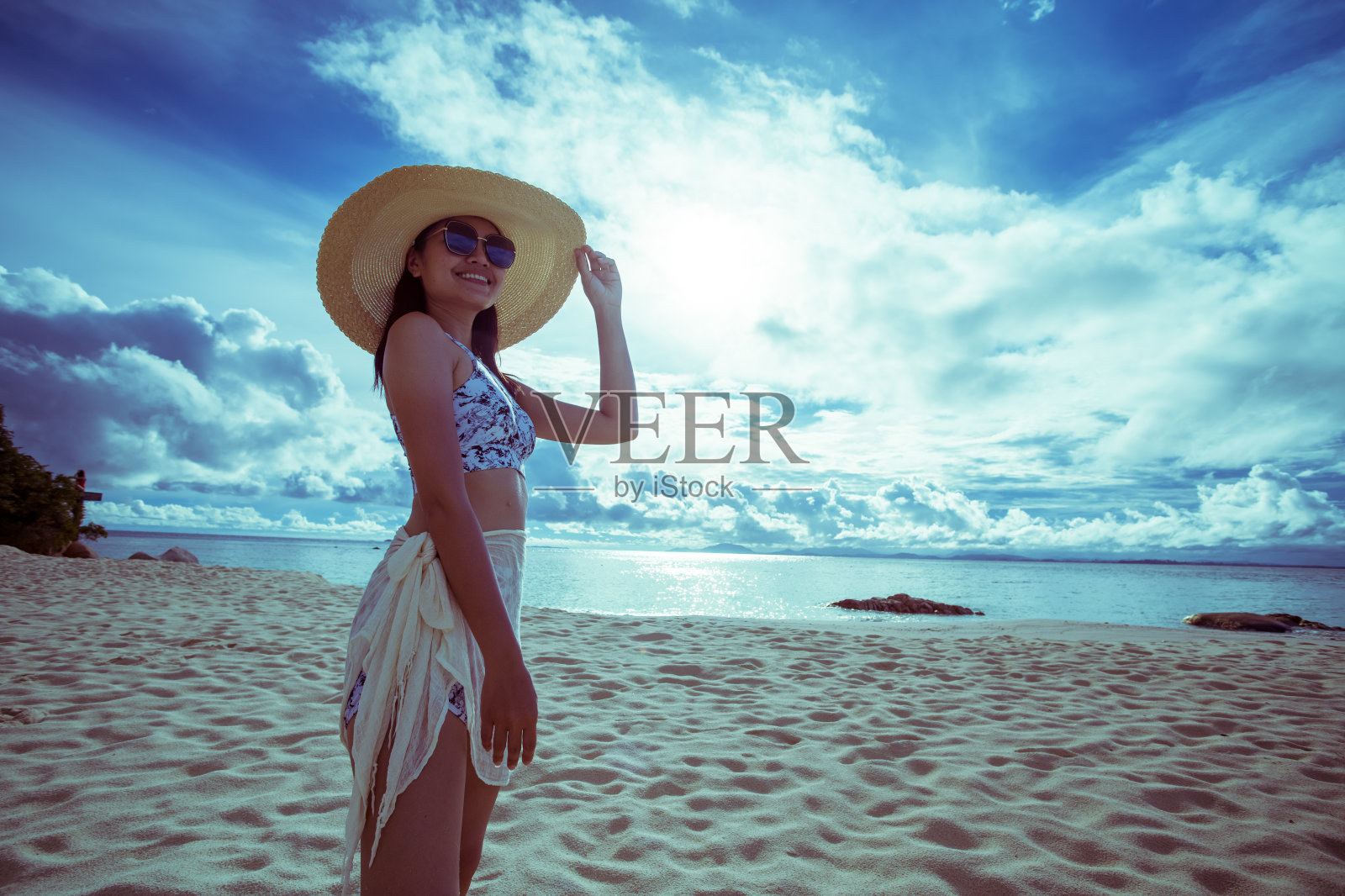 一名亚洲女子在晴朗的日子穿着比基尼和海帽在沙滩上照片摄影图片