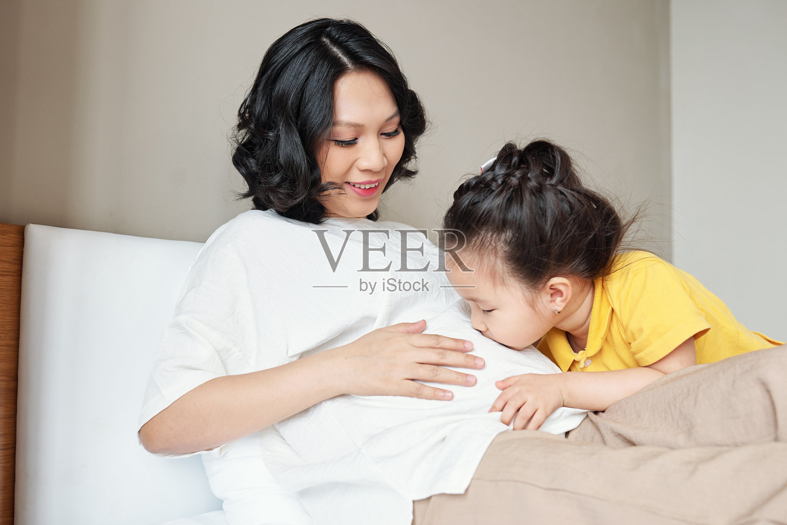 女孩亲吻怀孕母亲的肚子照片摄影图片