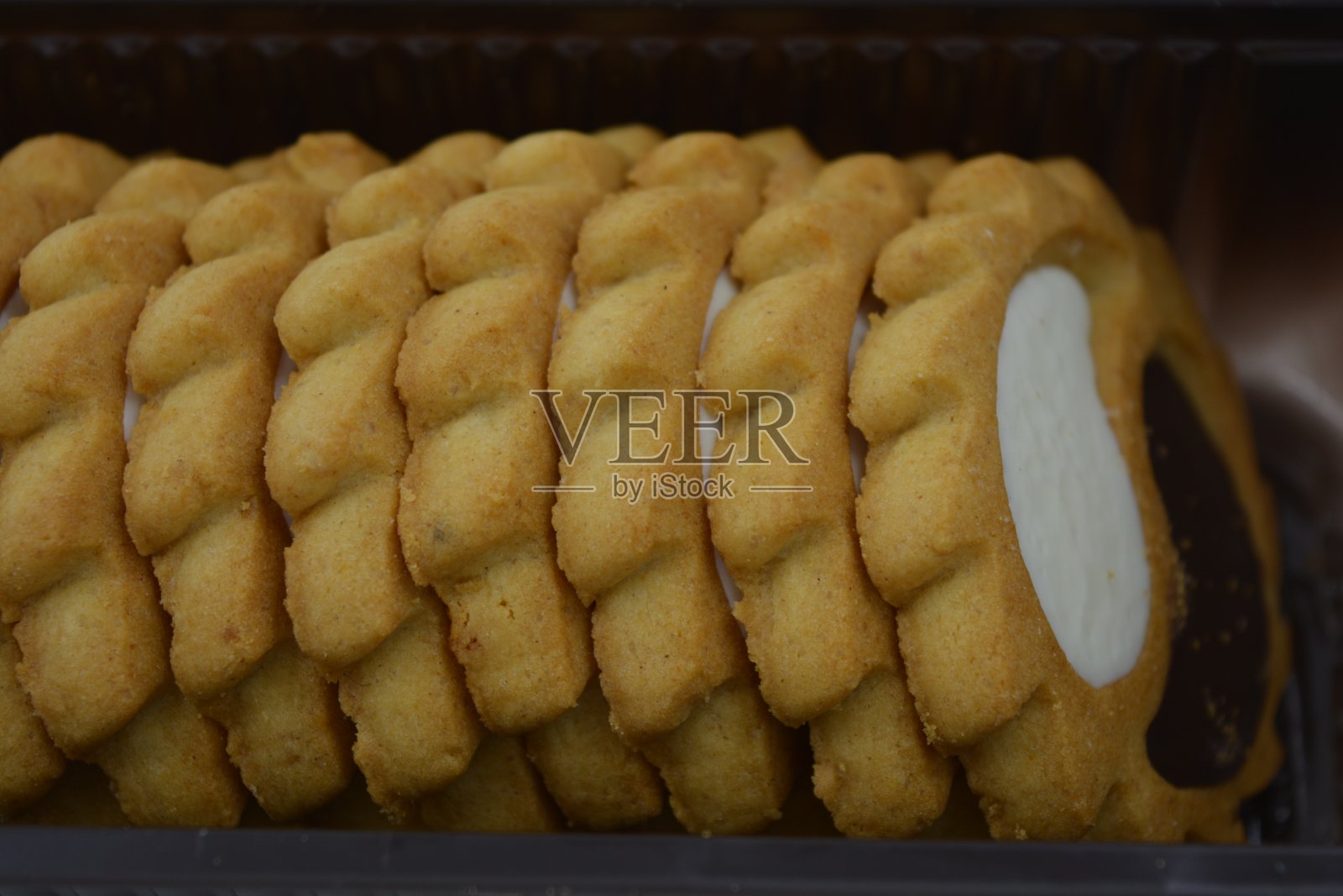 甜，金黄的酥饼，黄油饼干，甜馅糕点，牛奶和巧克力糊阳和阴的形式位于白色的背景和棕色的包装。照片摄影图片