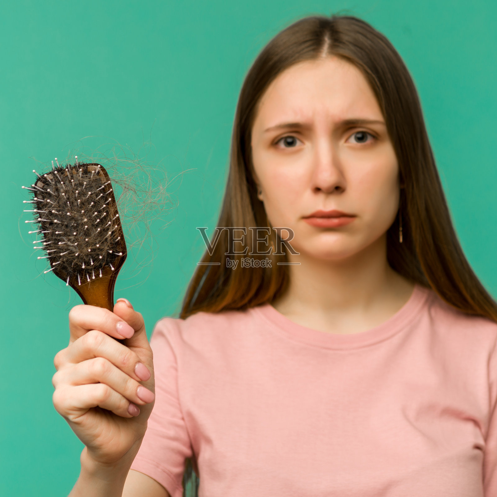 年轻女孩梳着梳子，头发有问题，背景是蓝色照片摄影图片
