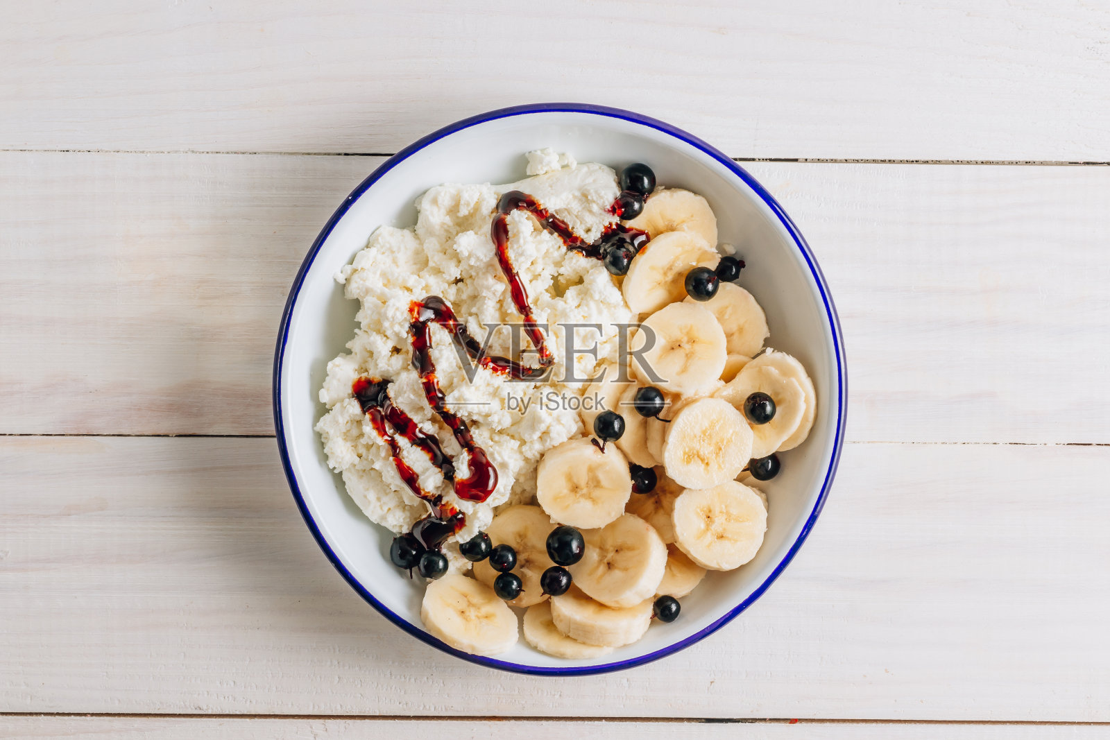 有机白软干酪配枣糖浆和香蕉是健康的早餐。白色的木头桌子照片摄影图片