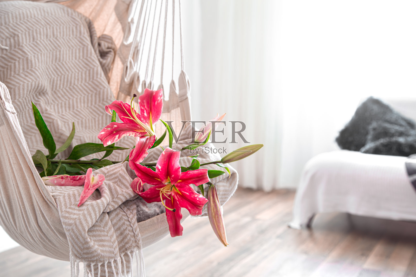 一张波西米亚风格的吊床，上面有漂亮的百合花。舒适的内部。休息和家的舒适的概念。照片摄影图片