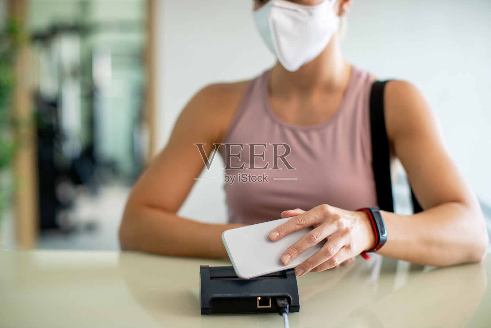 女运动员在健身俱乐部用智能手机登记的特写。照片摄影图片