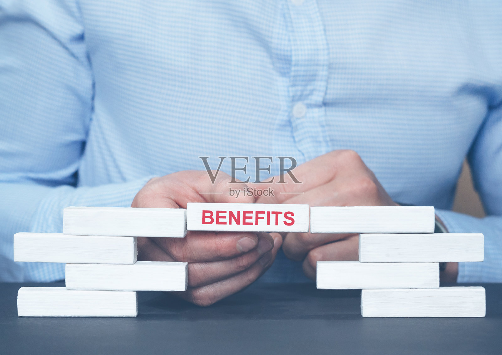 商人拿着一块刻着“利”字的木块。员工福利可以帮助你从竞争对手那里获得员工。业务发展走向成功和成长照片摄影图片