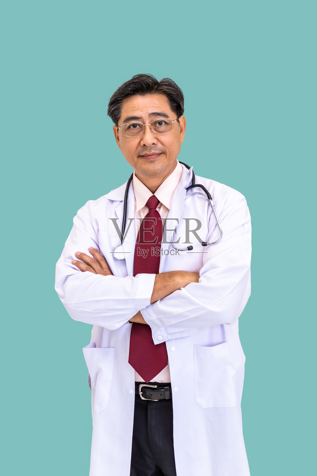 自信的亚洲男性男性医生站着，交叉双臂与听诊器在浅绿色的背景;看相机照片摄影图片