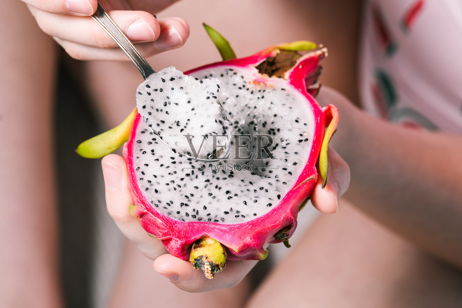 这个女孩正在用勺子吃热带水果。香甜新鲜，营养丰富。龙水果特写。照片摄影图片