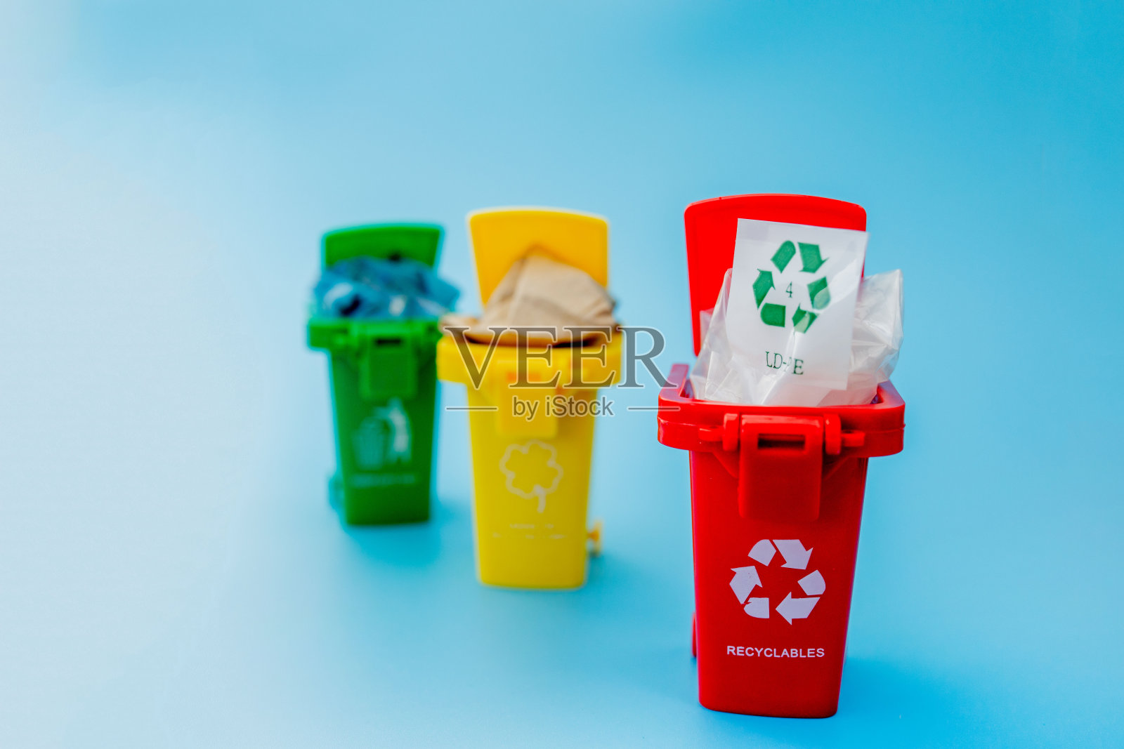 黄色，绿色和红色的回收箱与回收符号在蓝色背景。保持城市整洁，留下回收标志。自然保护的概念照片摄影图片