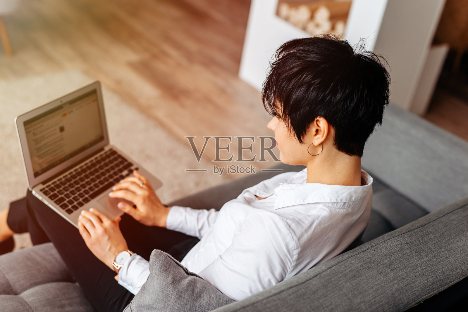 年轻的女商人坐在沙发上用笔记本电脑上网，从上面俯瞰照片摄影图片