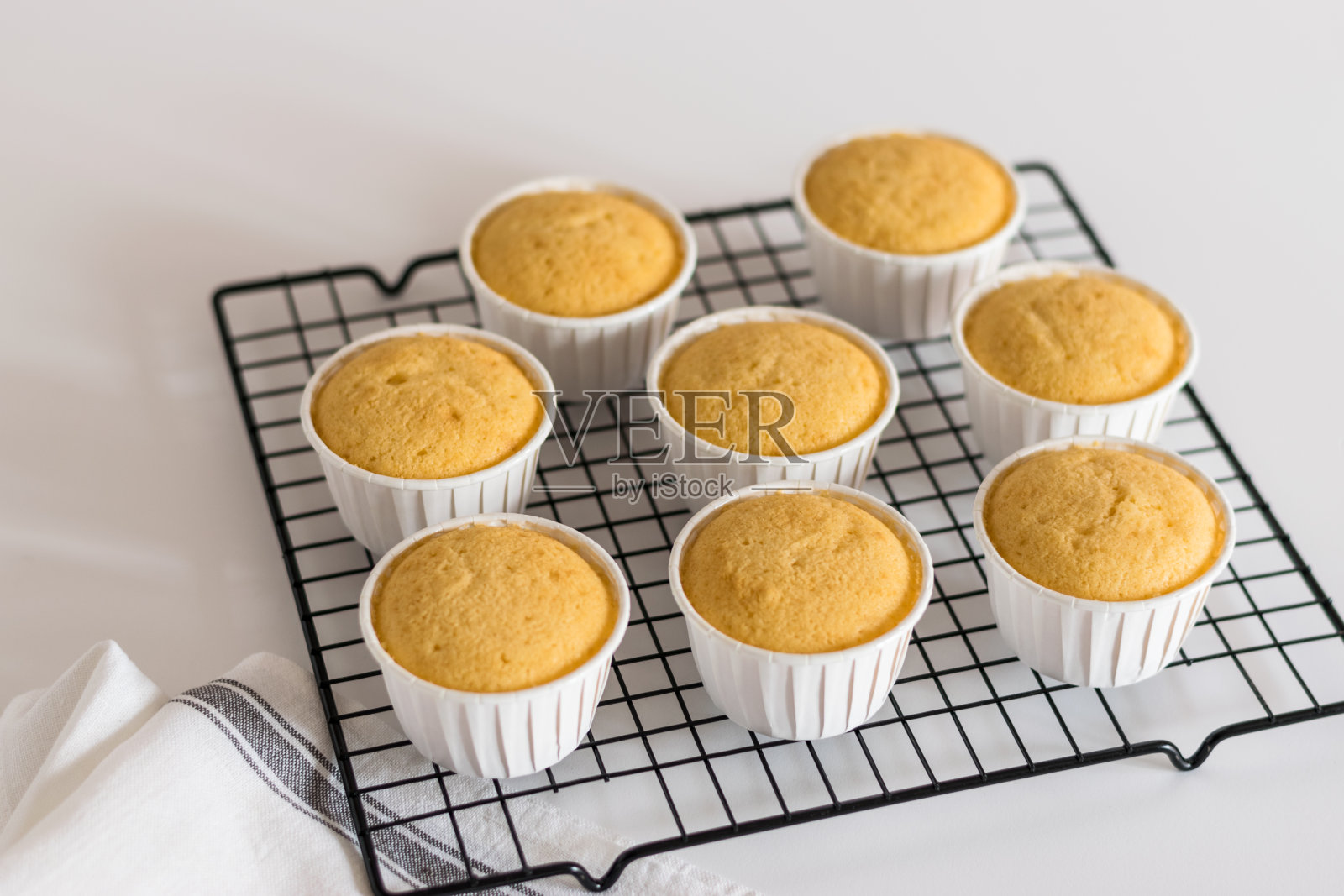 香草纸杯蛋糕装在白杯子里放在铁丝架上照片摄影图片