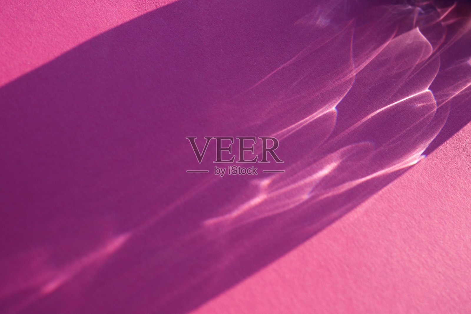 玻璃或水晶物体的美丽阴影。光线从粉红色背景的水中穿过。太阳强光阴影反射。照片摄影图片