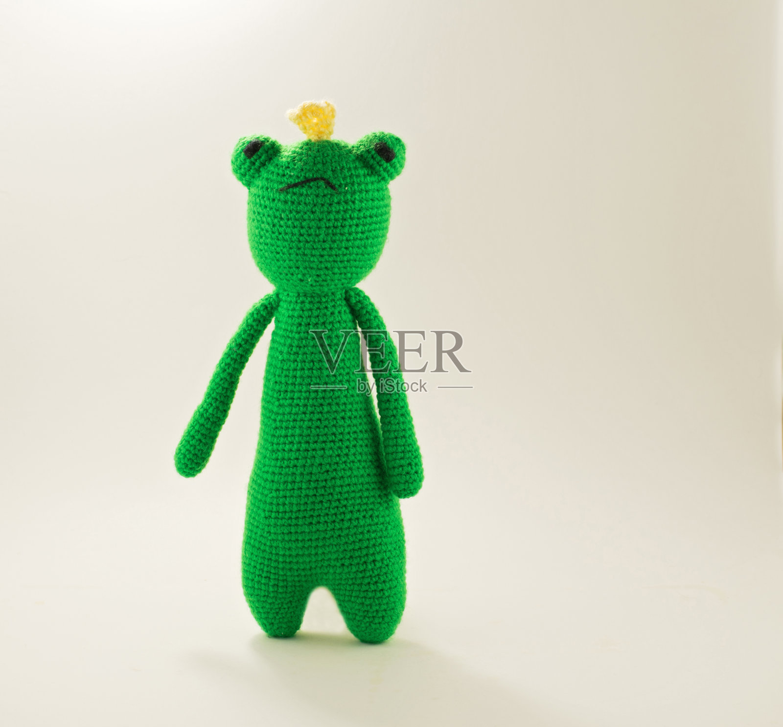 针织青蛙在白色的背景。手工玩具-绿色青蛙宝宝。照片摄影图片
