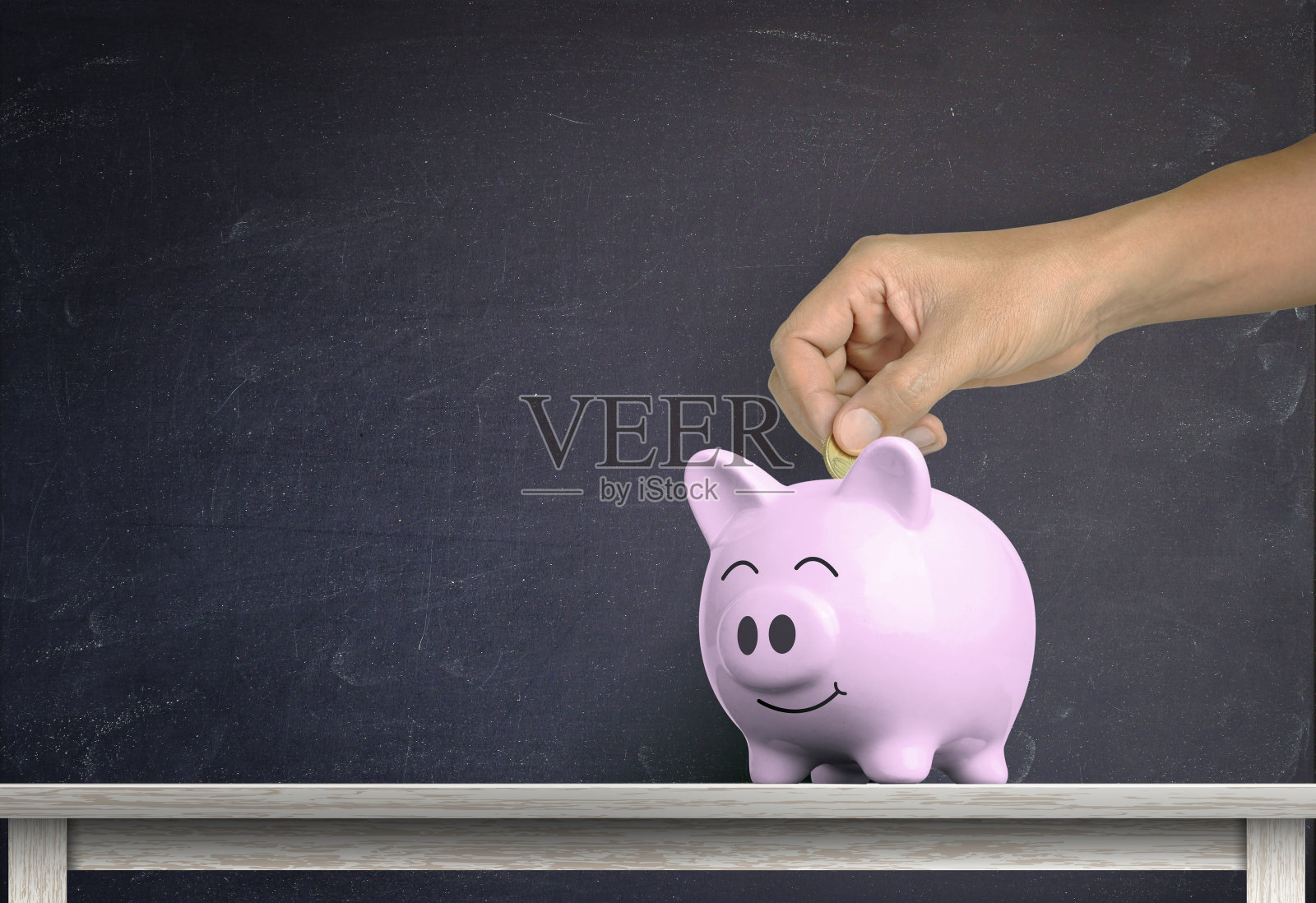 人的手把硬币扔进白色的储蓄罐里照片摄影图片