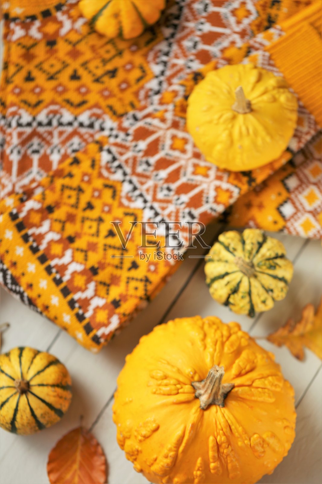 秋季服装。时尚的秋季毛衣。秋季销售和折扣时间。秋季时尚。带有图案的棕色暖毛衣和黄色南瓜，背景为木灰色。照片摄影图片