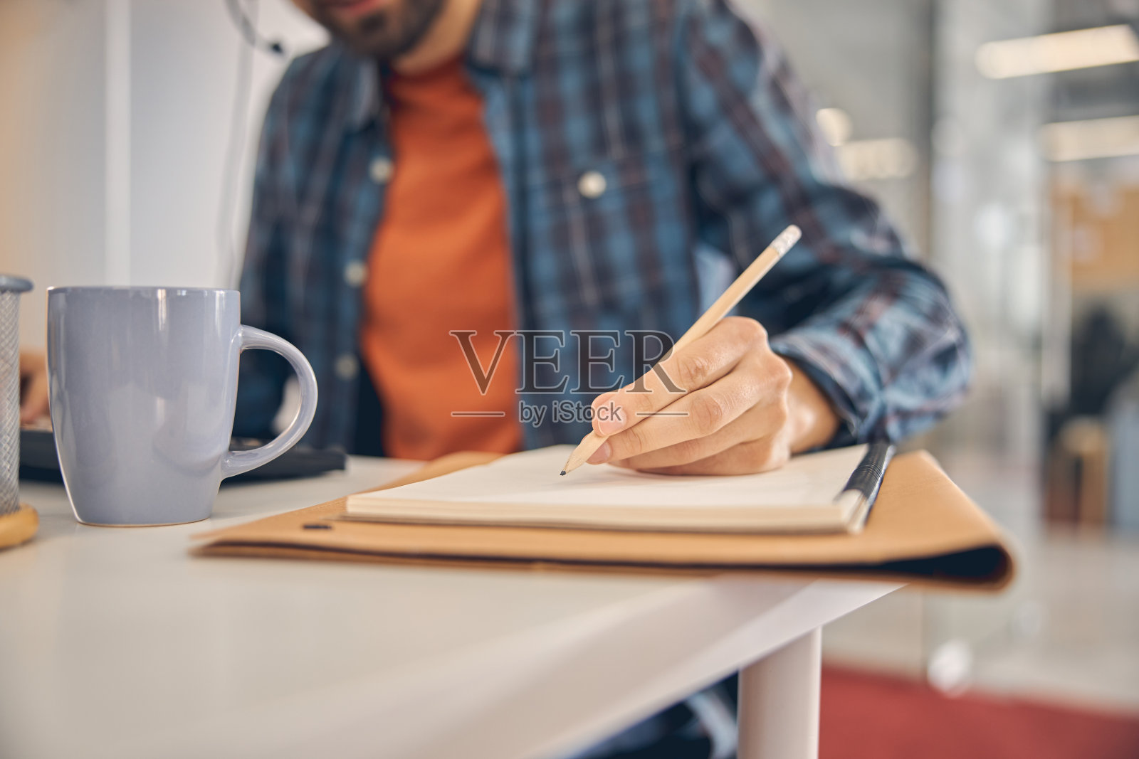 工作时在螺旋笔记本上写字的年轻人照片摄影图片