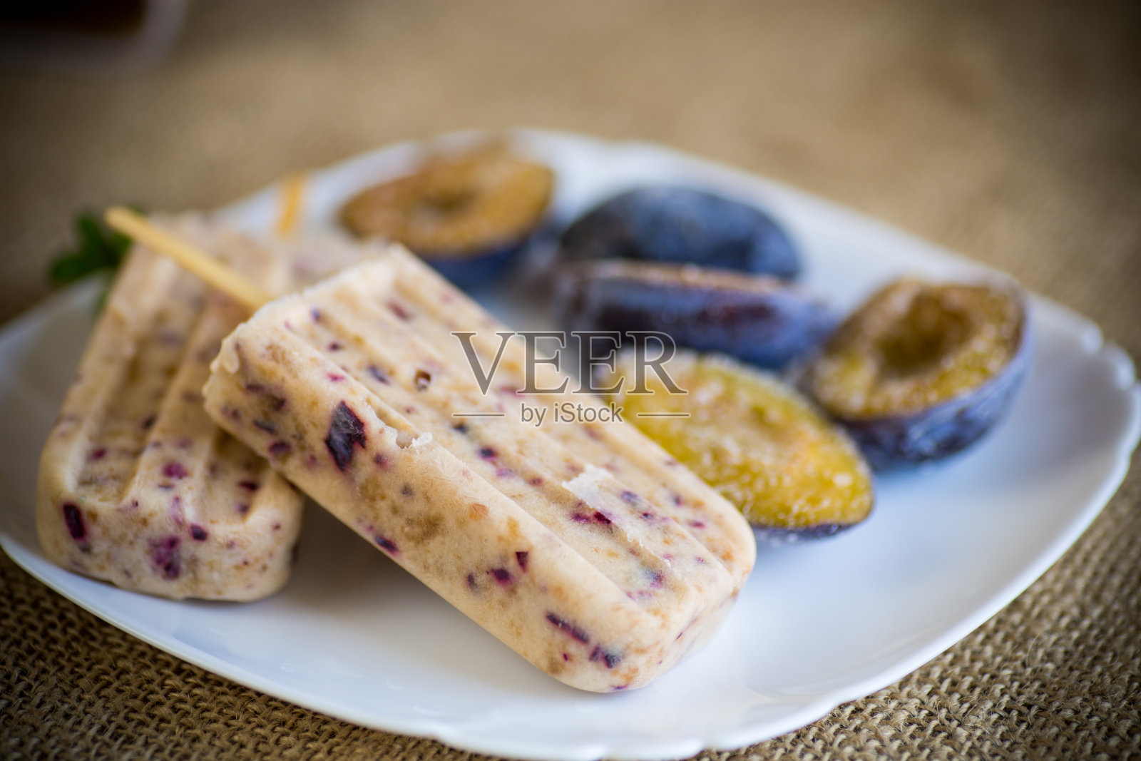 梅子自制甜冰淇淋，用棒子夹上梅子片，装在盘子里照片摄影图片