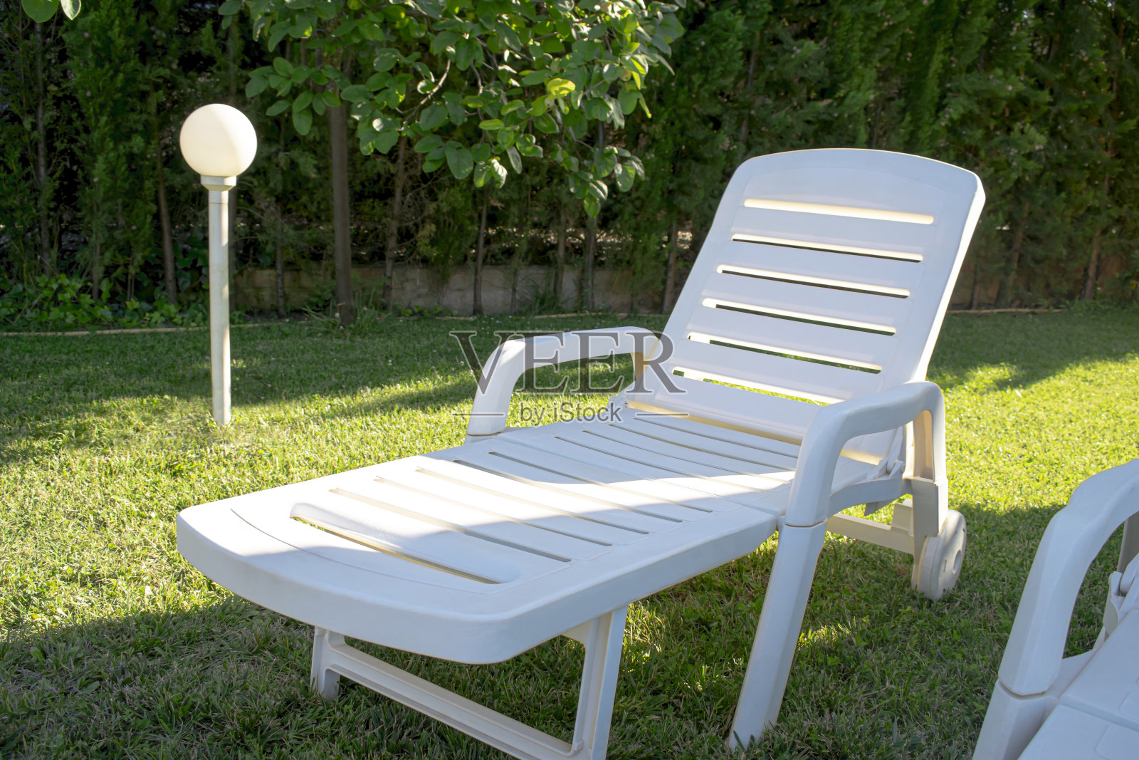 躺椅在草坪上，有灯笼照明和绿树成荫的区域。照片摄影图片