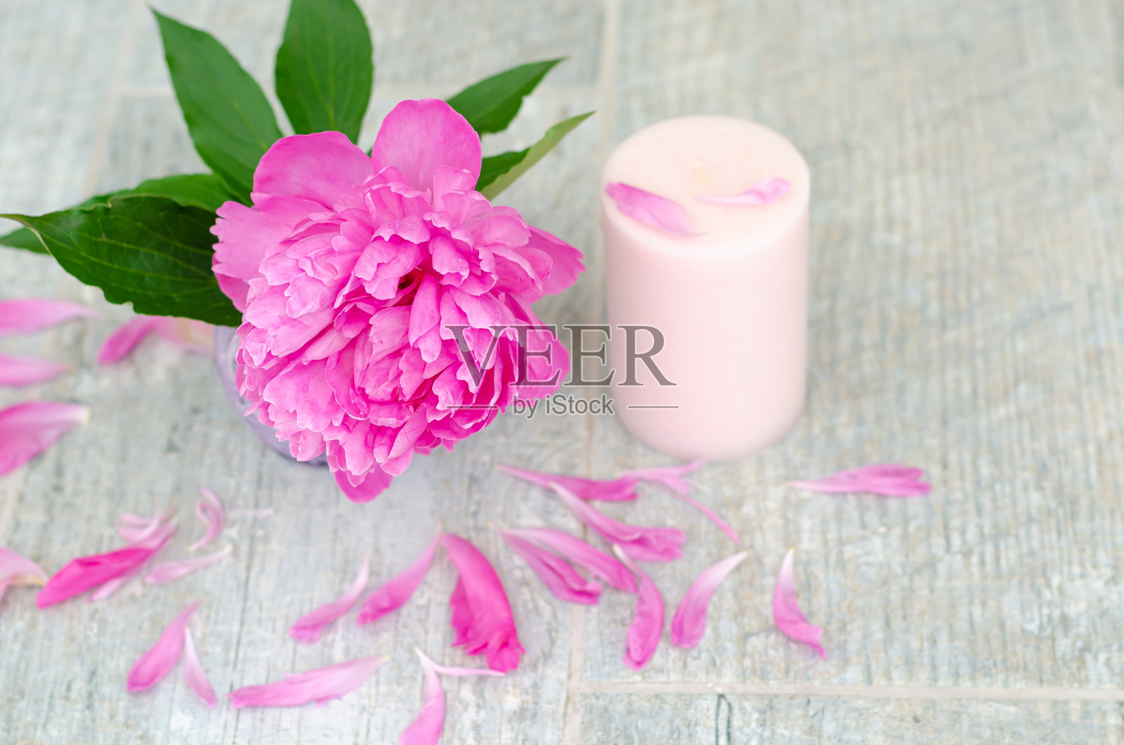 美丽的粉红色牡丹花和白色的蜡烛在灰色的石头背景与复制空间的文字，俯视图。贺卡。照片摄影图片