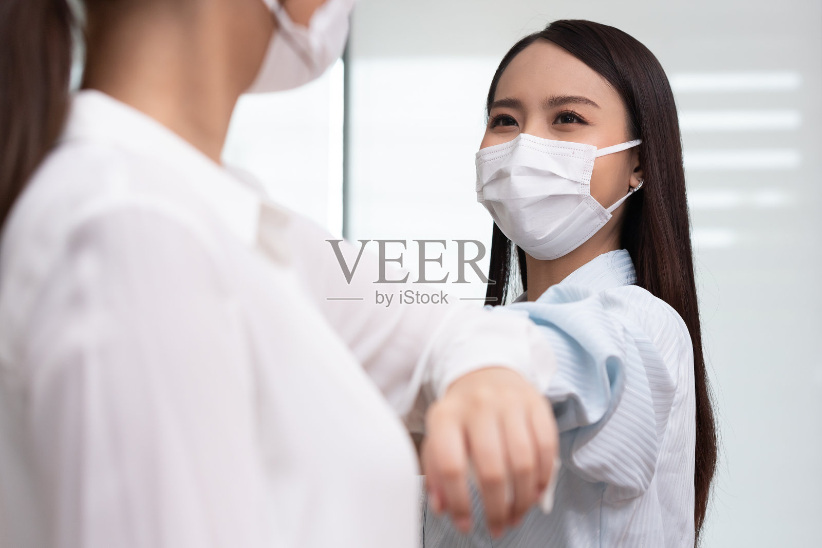 商务女性用肘打招呼而不是握手。照片摄影图片