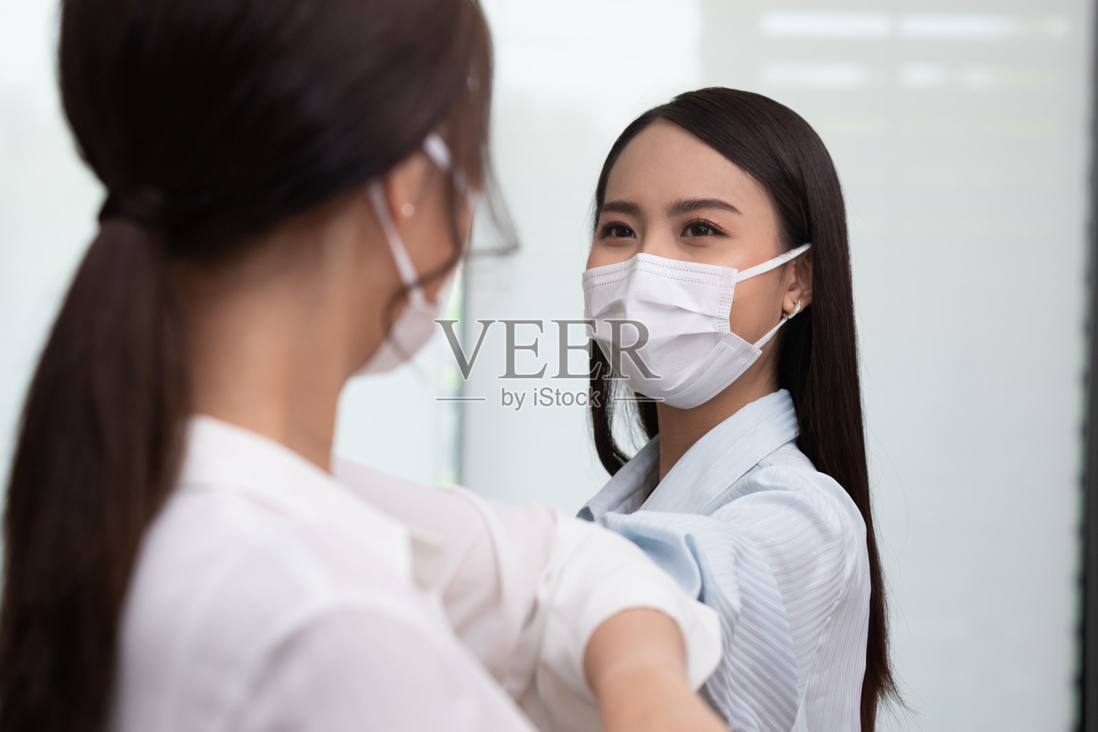 商务女性用肘打招呼而不是握手。照片摄影图片