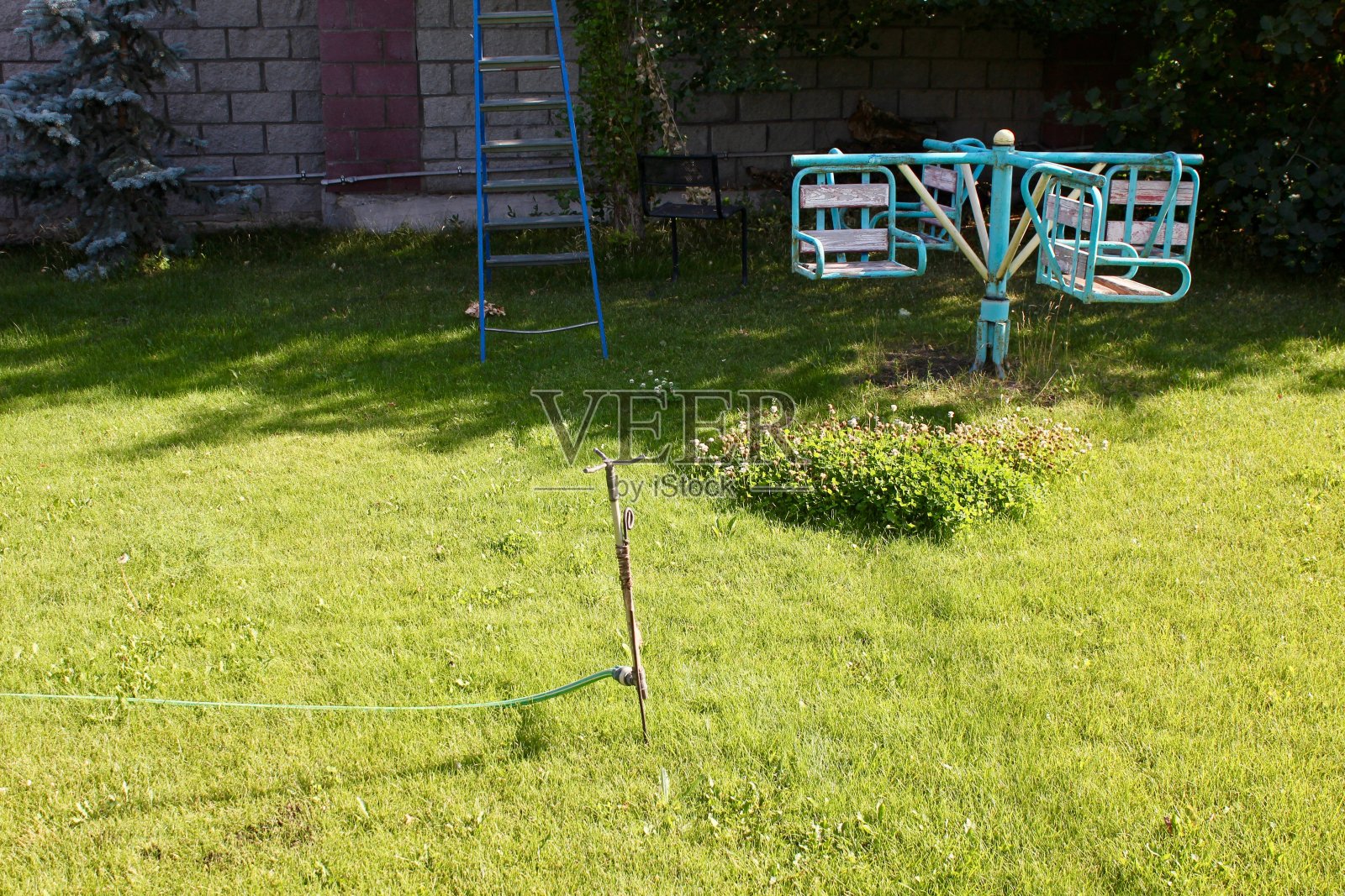 在街上的公寓楼院子里的操场上有滑梯，楼梯，绿色的草地上有秋千照片摄影图片