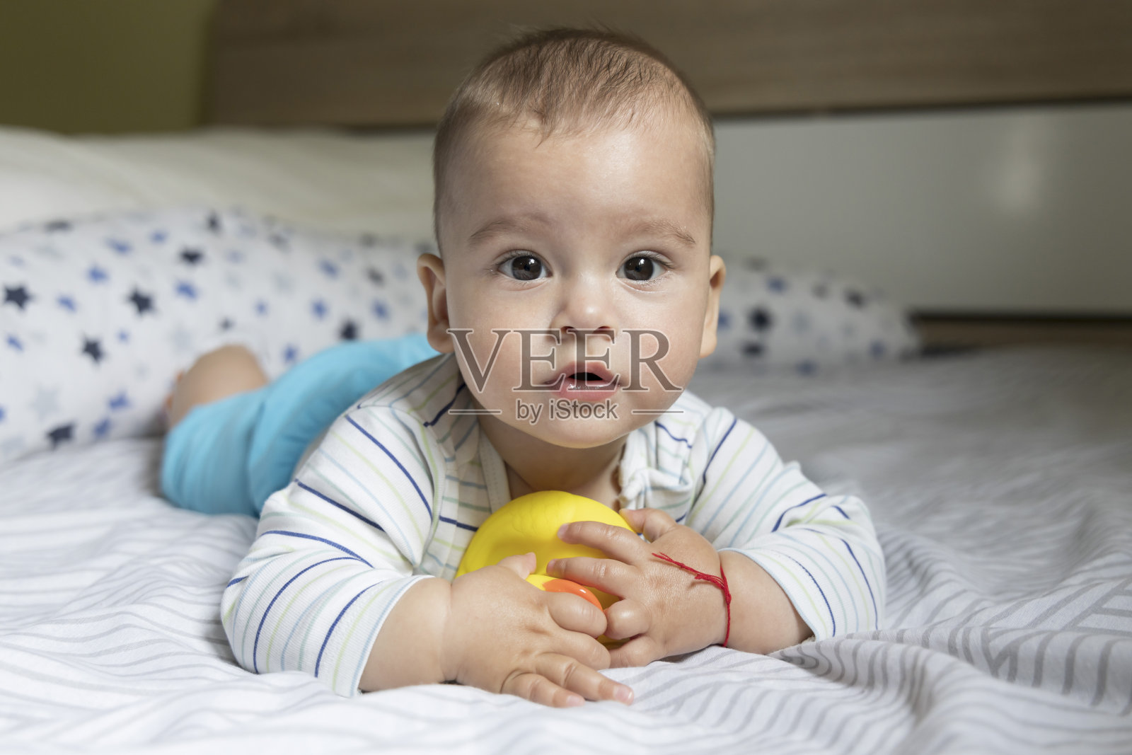 一个下雨天，小男孩和一只黄色的鸭子在床上玩照片摄影图片