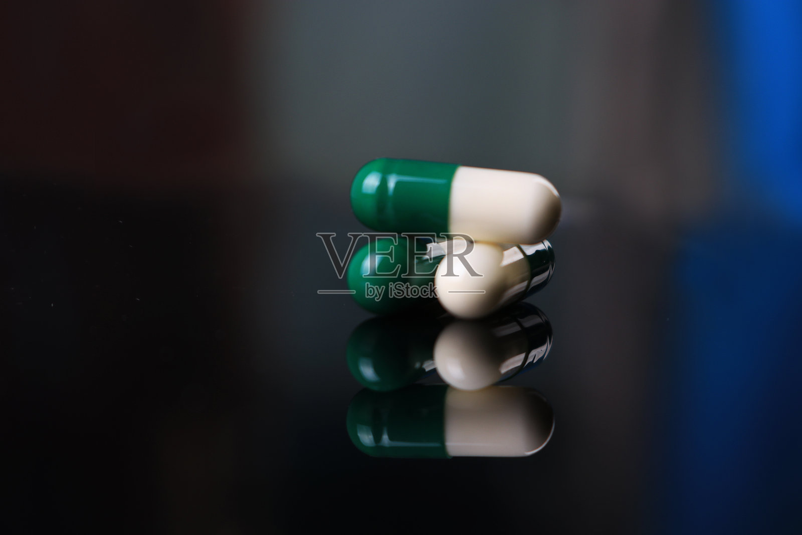 黑色背景下的绿色和白色胶囊照片摄影图片