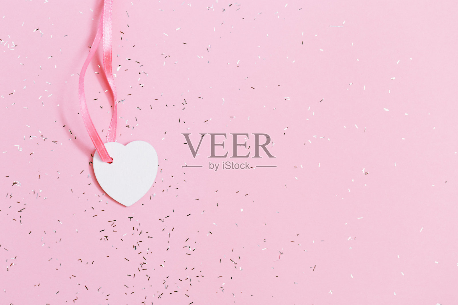 白色小心在粉红色的纸背景覆盖亮片。照片摄影图片