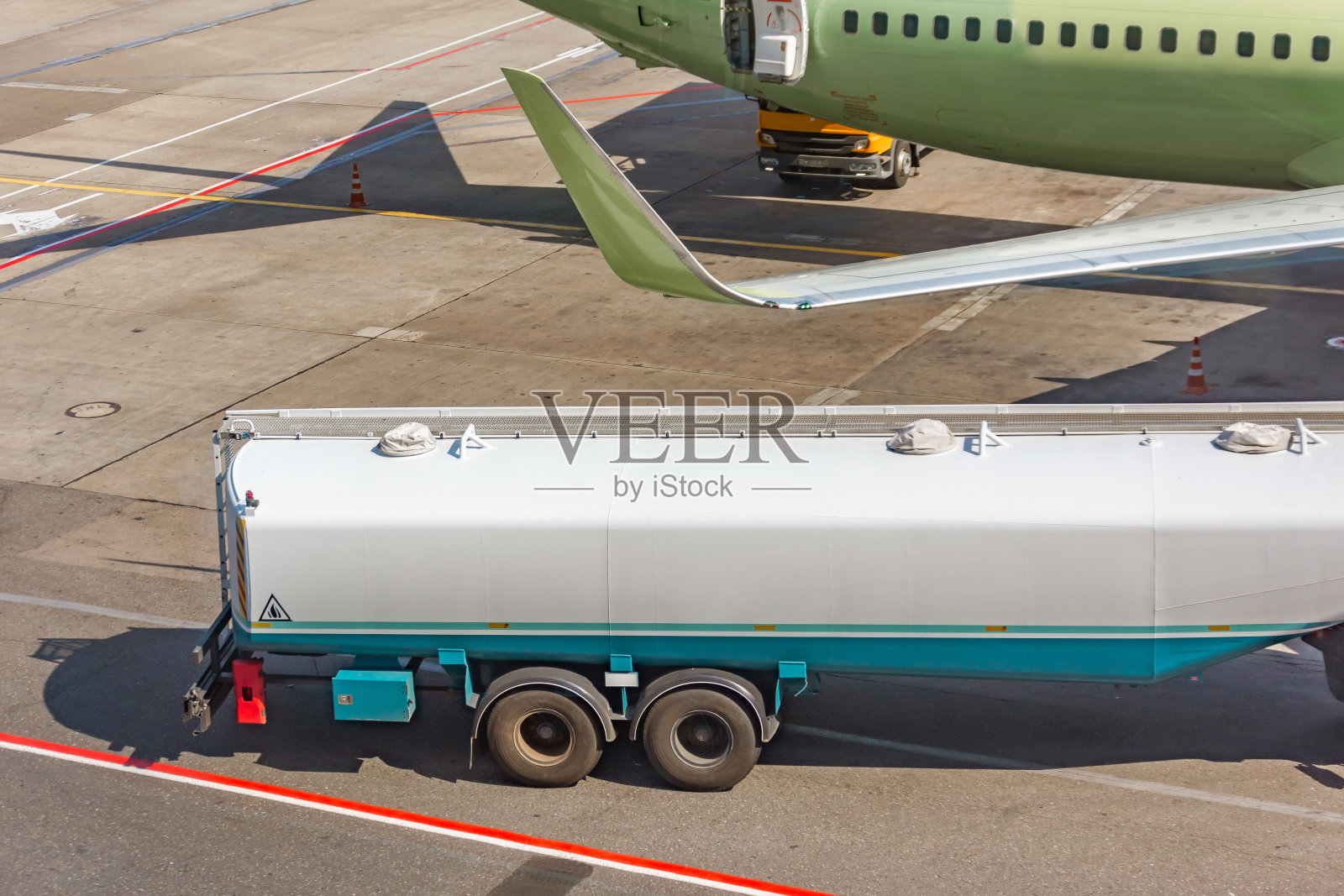 油罐车在机场给一架飞机加油。照片摄影图片