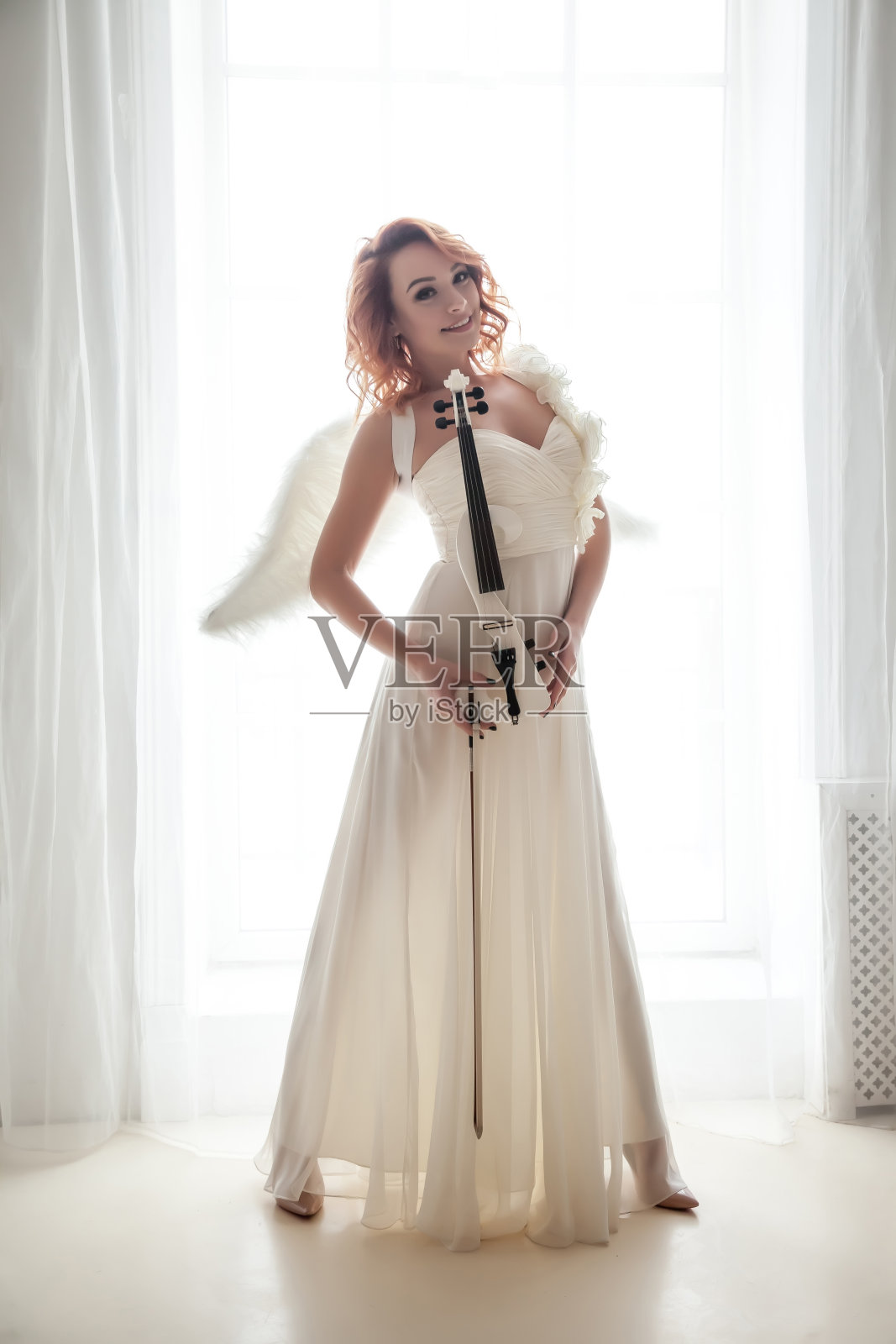 漂亮苗条的女人，带着小提琴和翅膀照片摄影图片