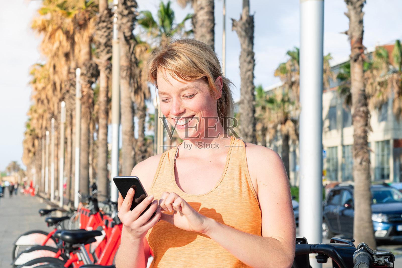 迷人的金发女人在看电话照片摄影图片