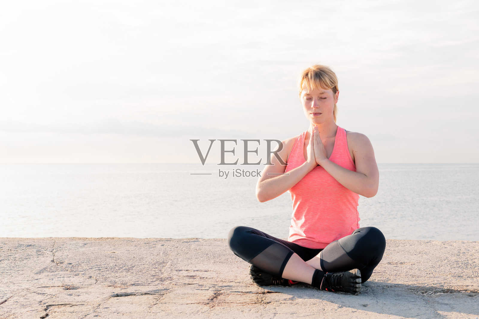 坐在大海前练瑜伽的女人照片摄影图片