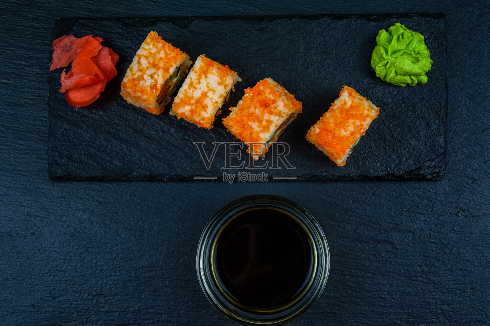 寿司费城卷，三文鱼，米饭，奶酪，黄瓜，鳄梨和鱼子酱放在一块板上。日本的食物。俯视图照片摄影图片