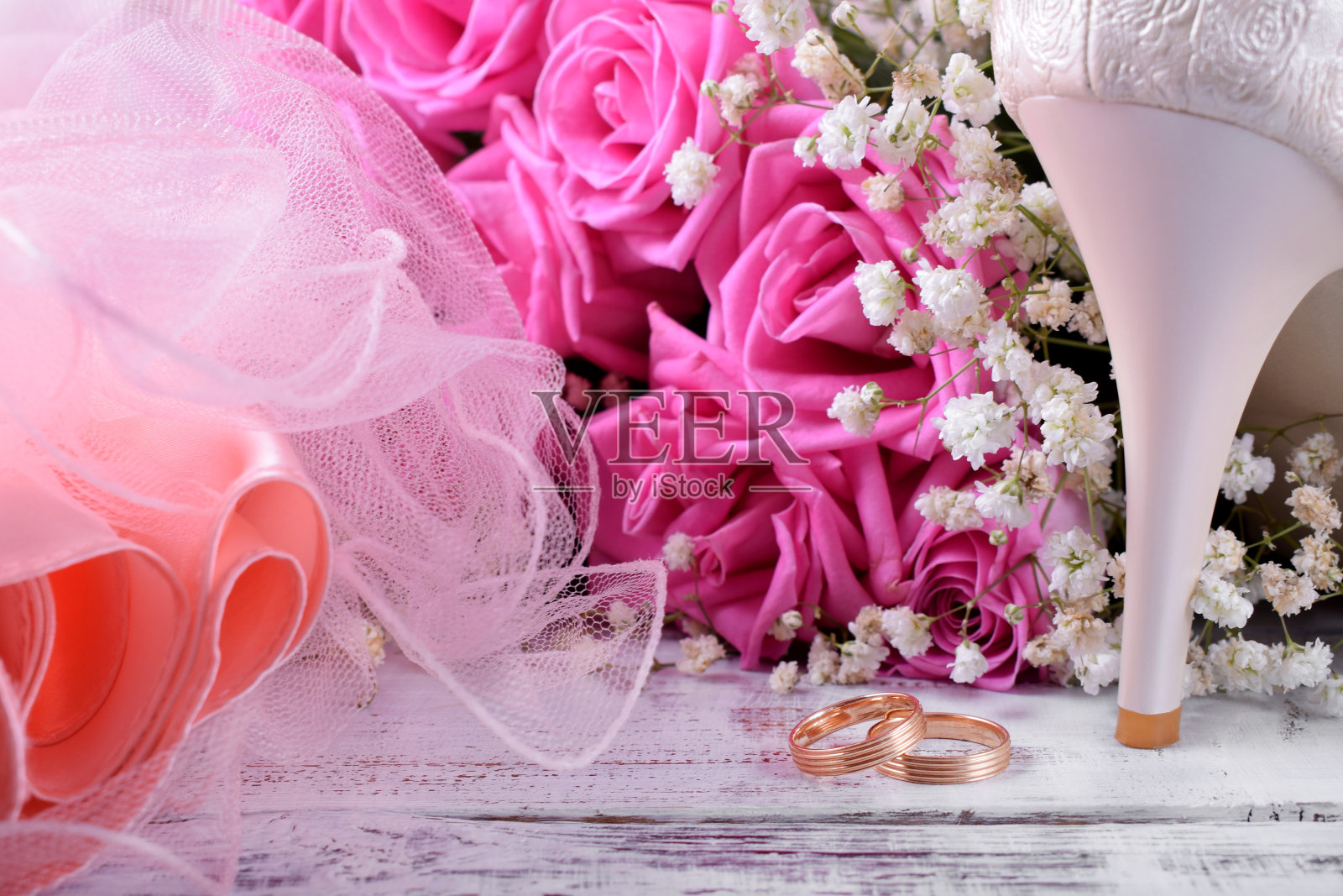 白色高跟鞋，一对订婚戒指和一束粉色玫瑰照片摄影图片