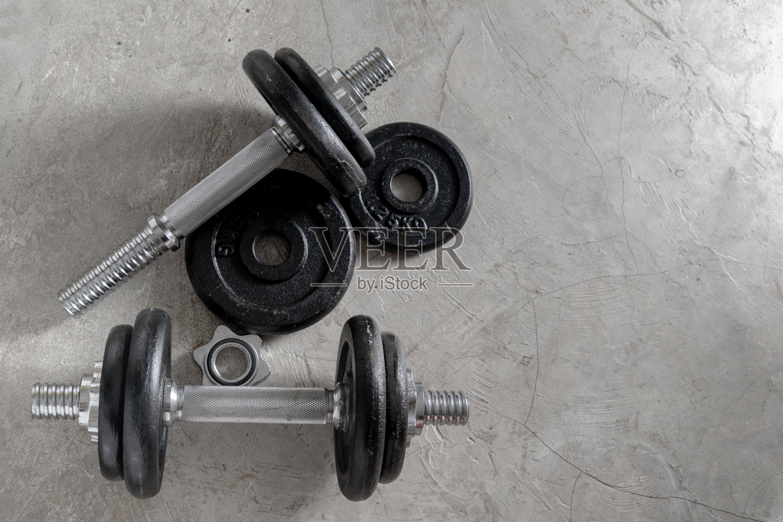 健身房水泥地板上的钢制哑铃是为健身者准备的照片摄影图片