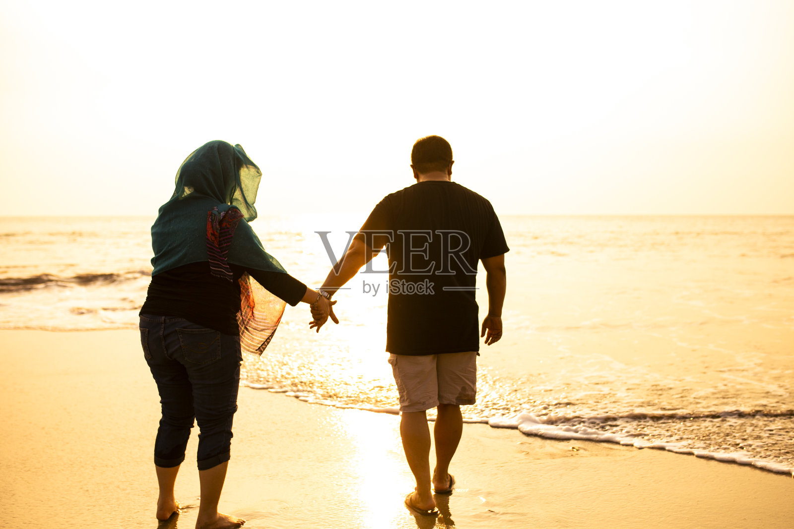 在海滩上牵着手的幸福夫妇照片摄影图片