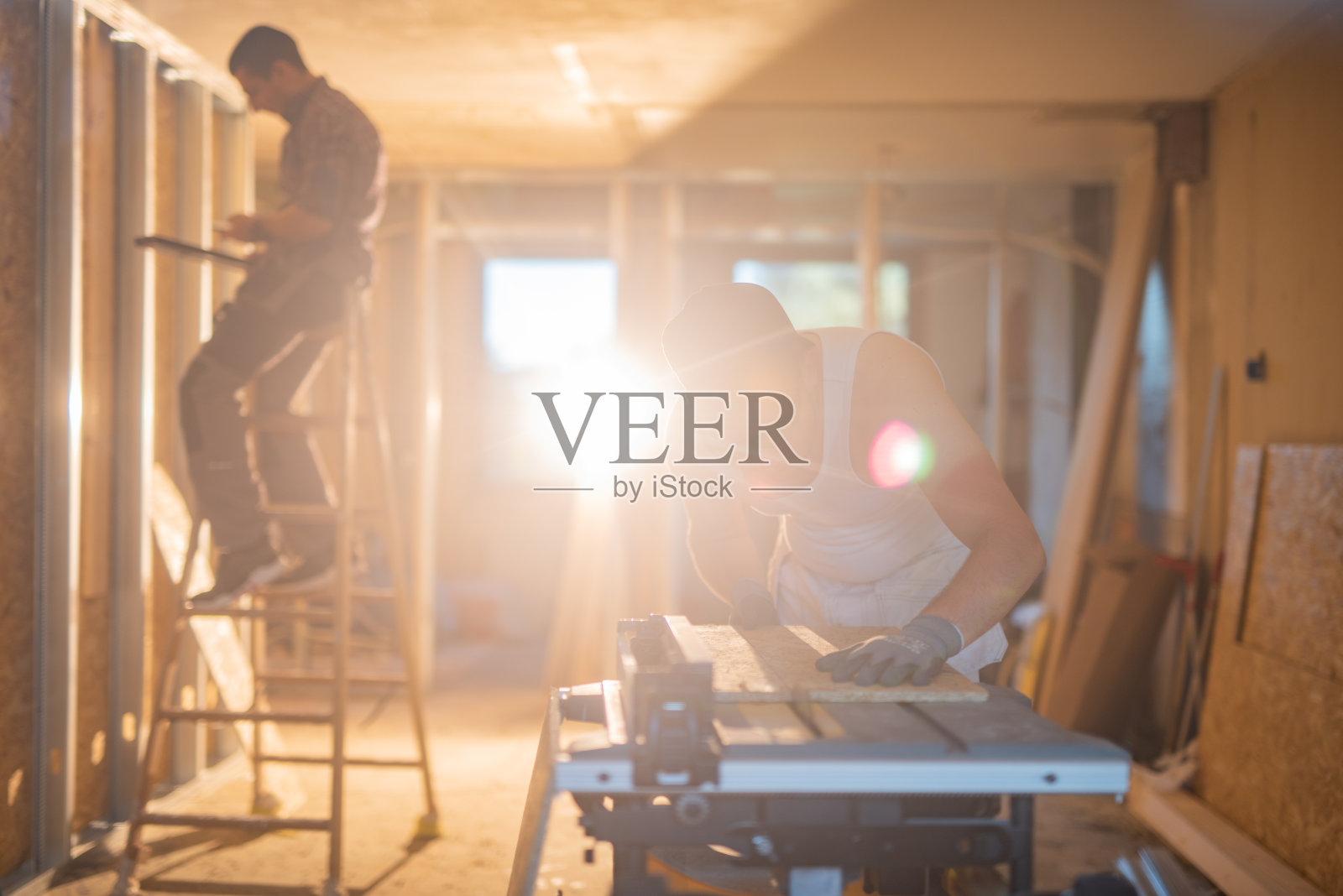 建筑工人在工地用圆锯切木板。照片摄影图片