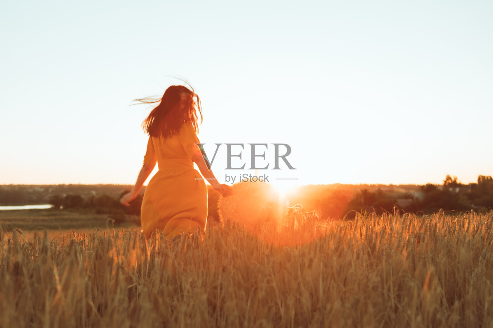 穿着黄色背心裙的女人走过麦田照片摄影图片