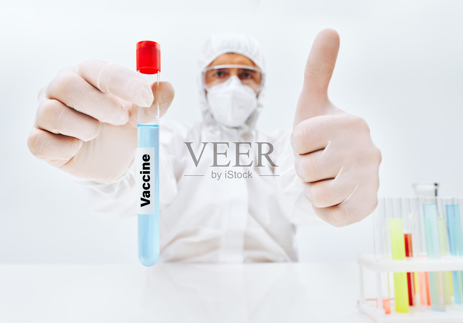 个人防护装备的科学家拿着预防传染病的疫苗并竖起大拇指照片摄影图片
