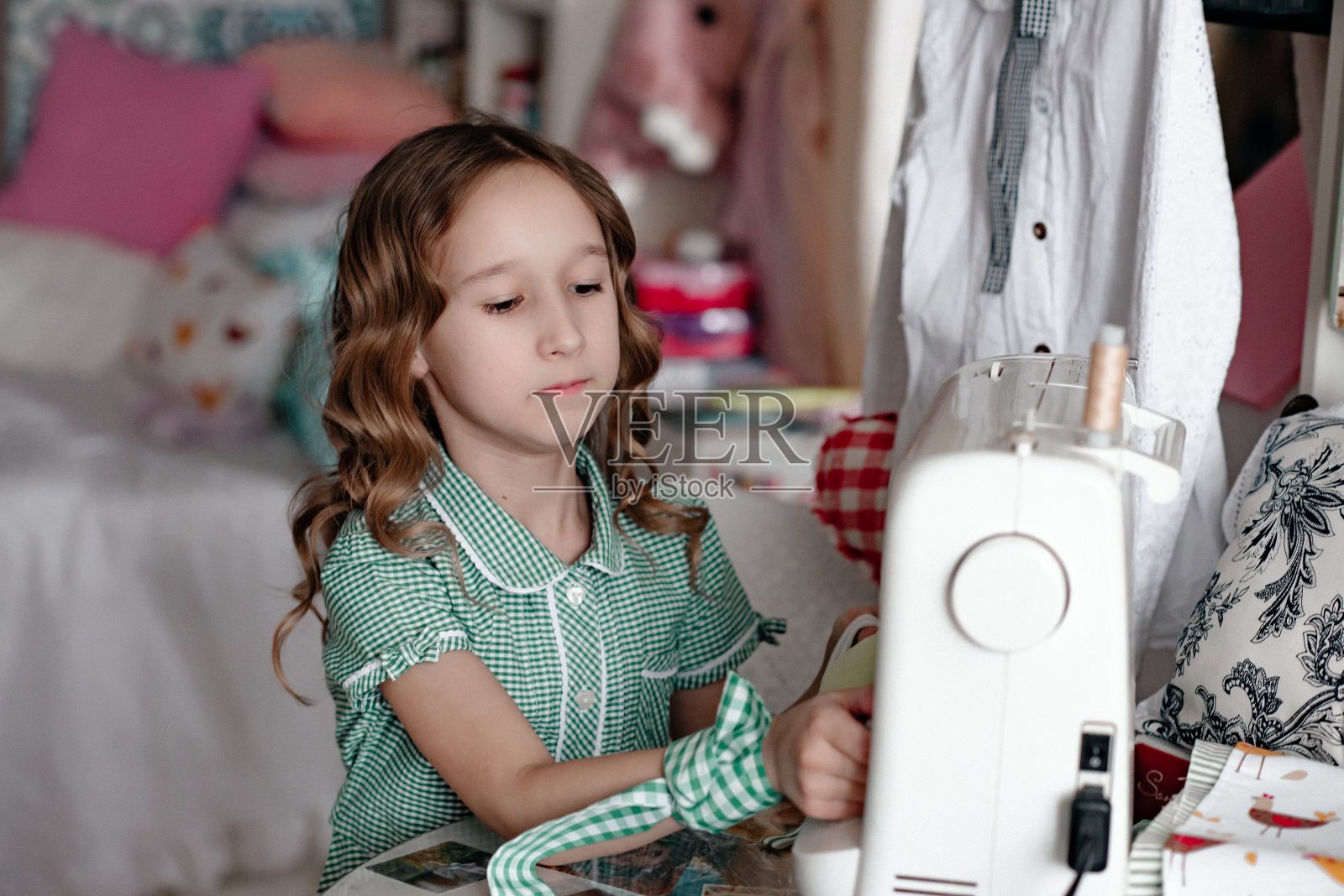 一个微笑的女孩正在她的房间里做针线活。照片摄影图片