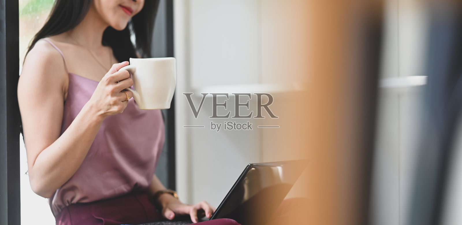 一个漂亮的女人正坐在客厅的地板上，用着电脑休息。照片摄影图片