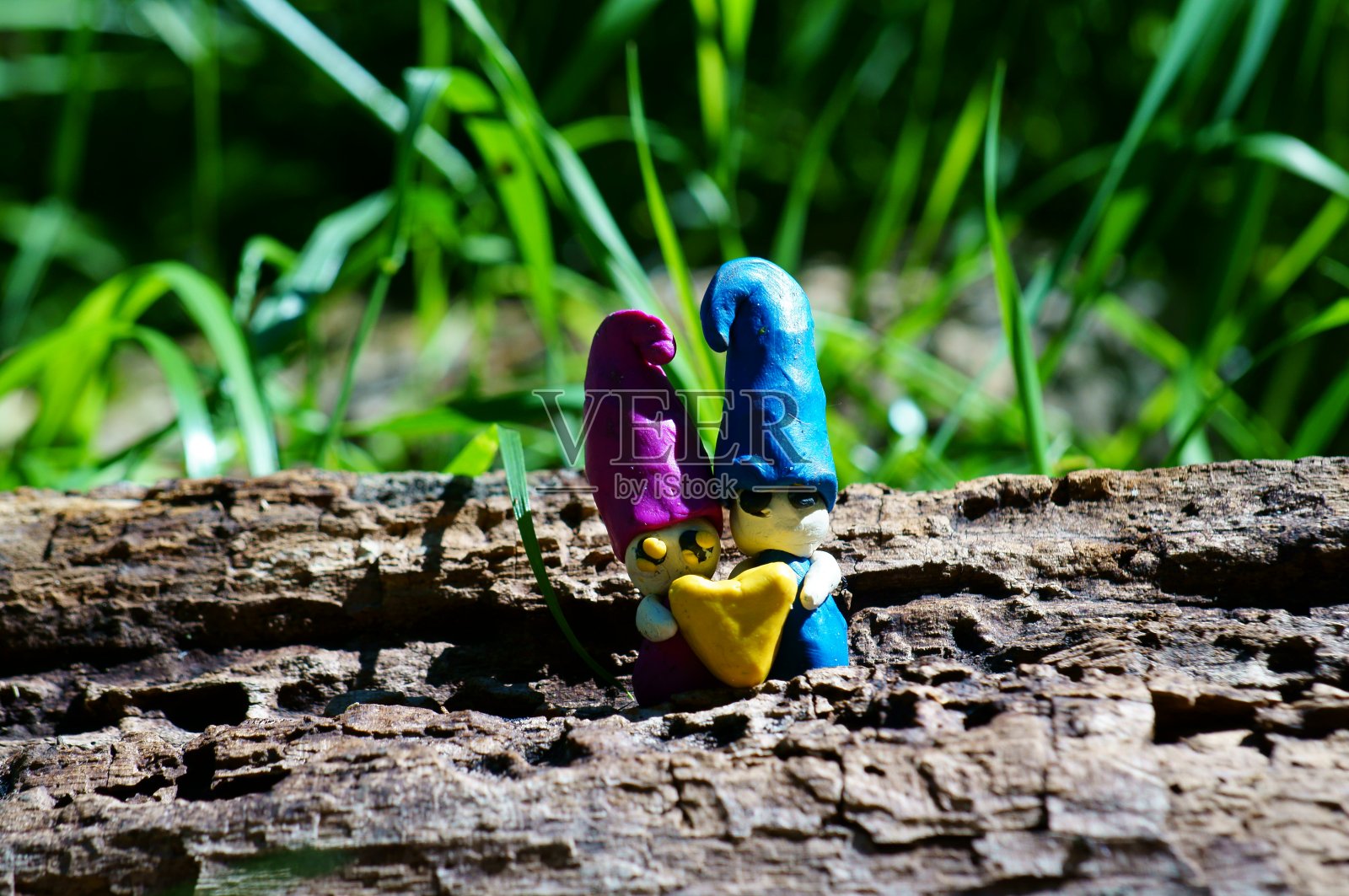 两个相爱的小矮人捧着一颗心。照片摄影图片