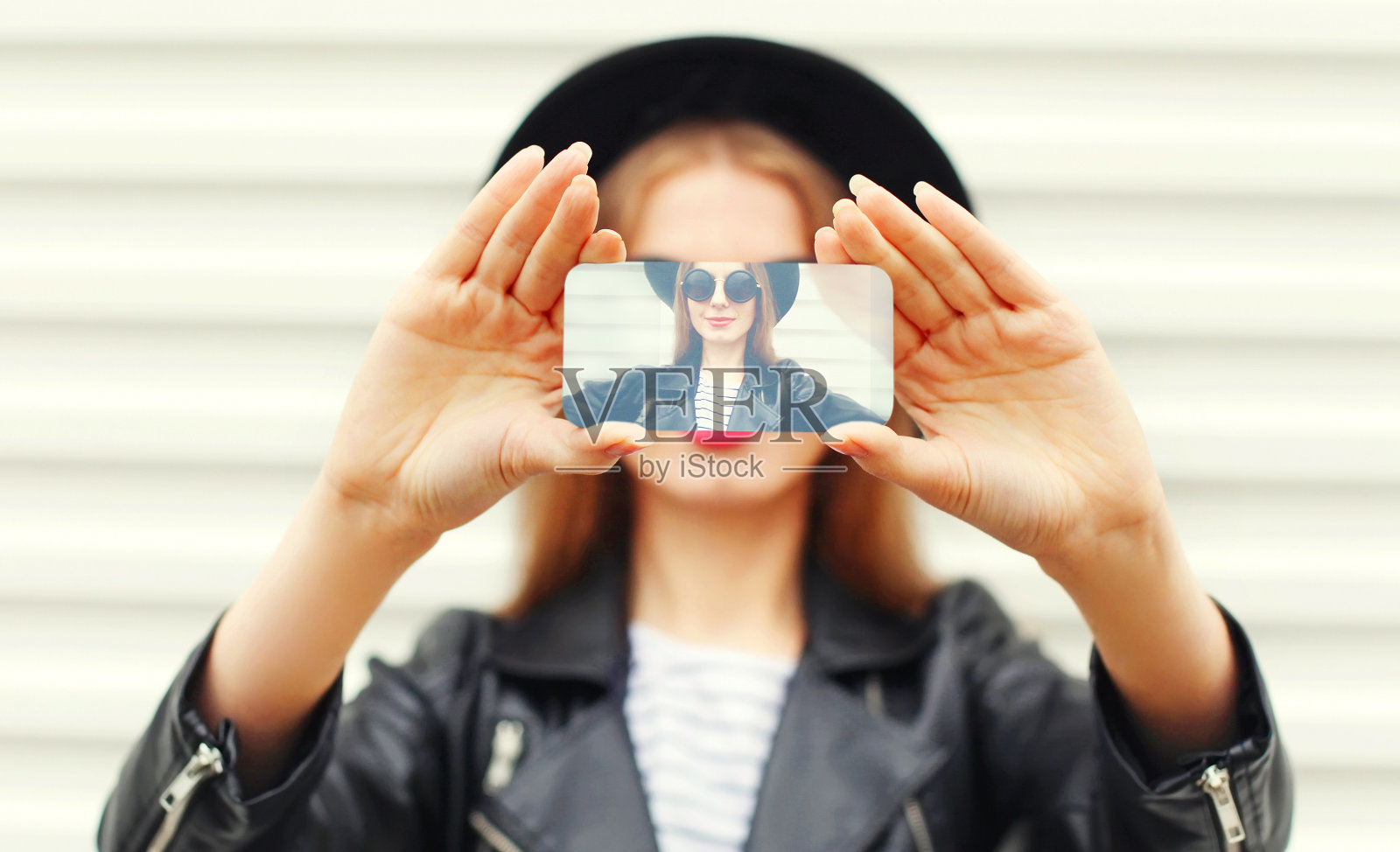 近距离的女人用智能手机自拍墙背景照片摄影图片