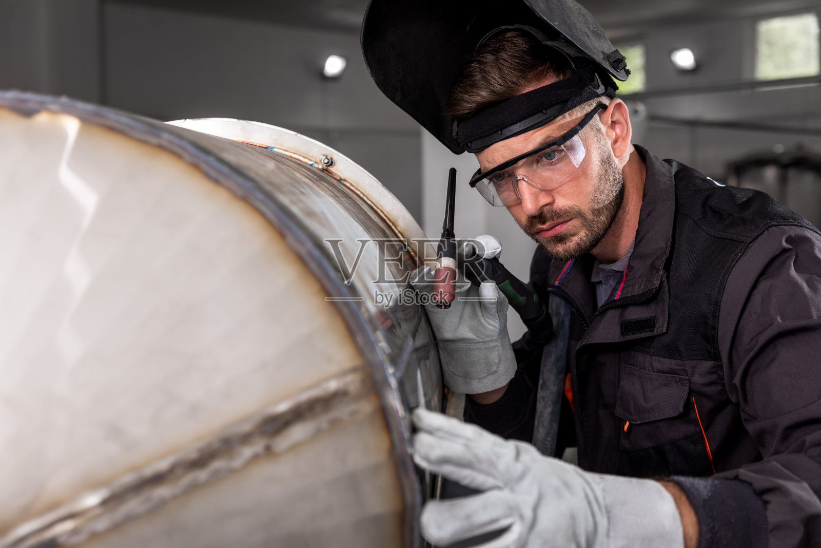 工业工人防护面罩焊接车间金属结构。照片摄影图片