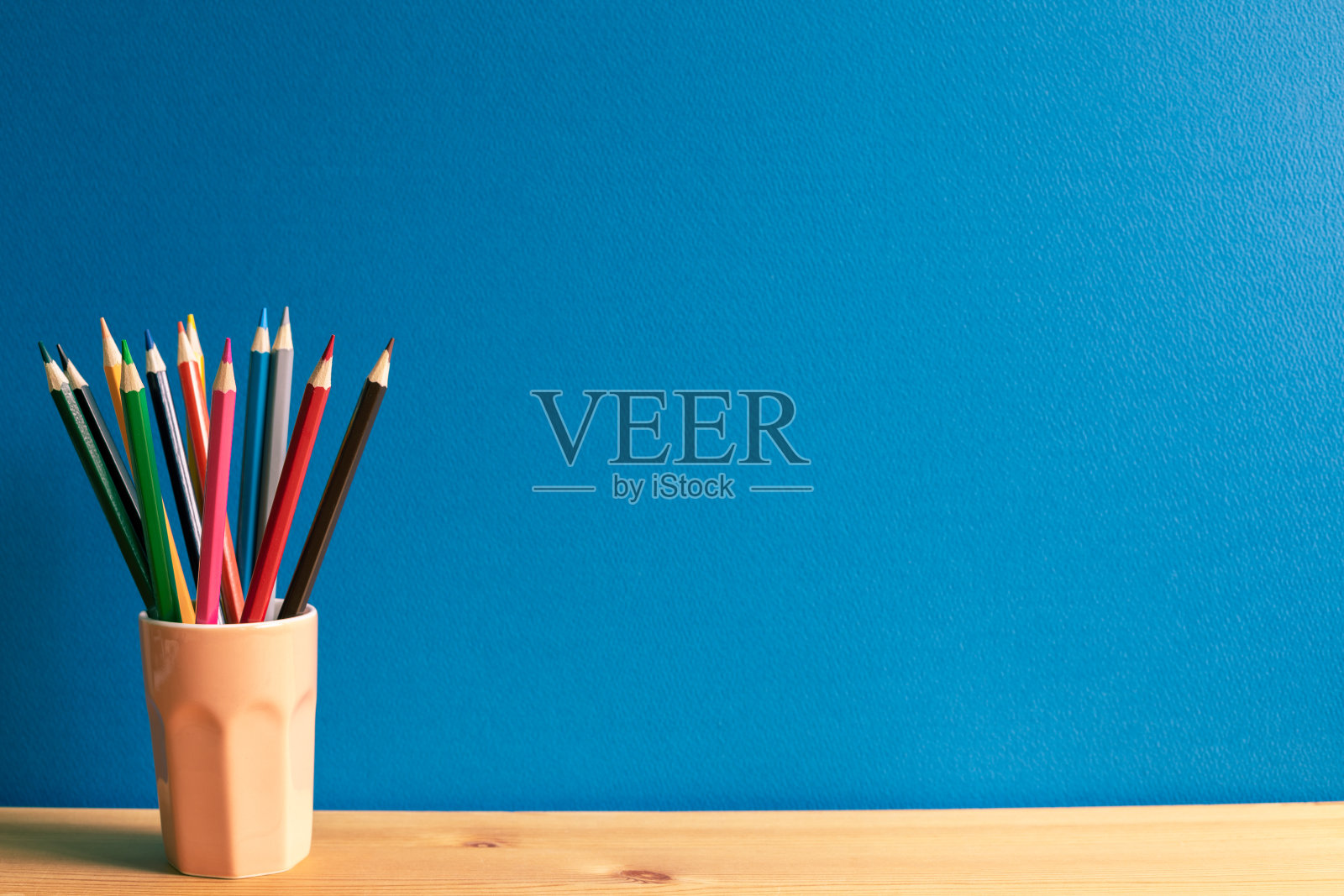 蓝色背景木桌上的彩色铅笔架照片摄影图片