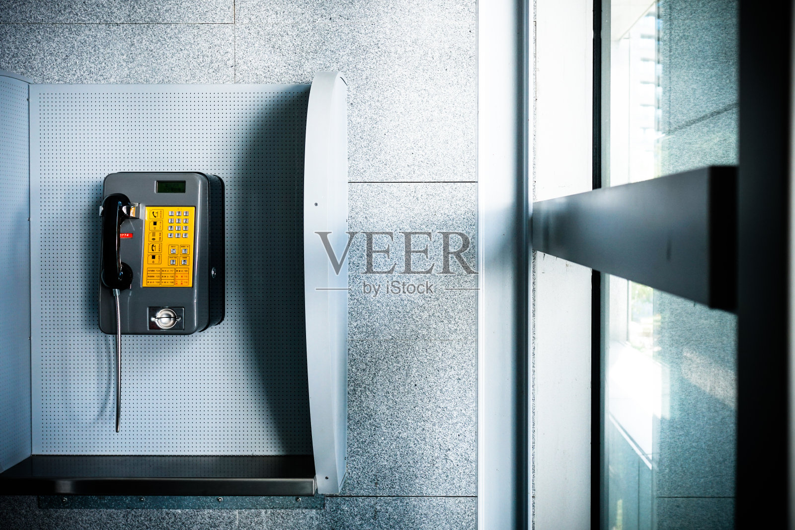 近距离观看现代建筑中的公用电话。前景模糊，焦点在背面。照片摄影图片