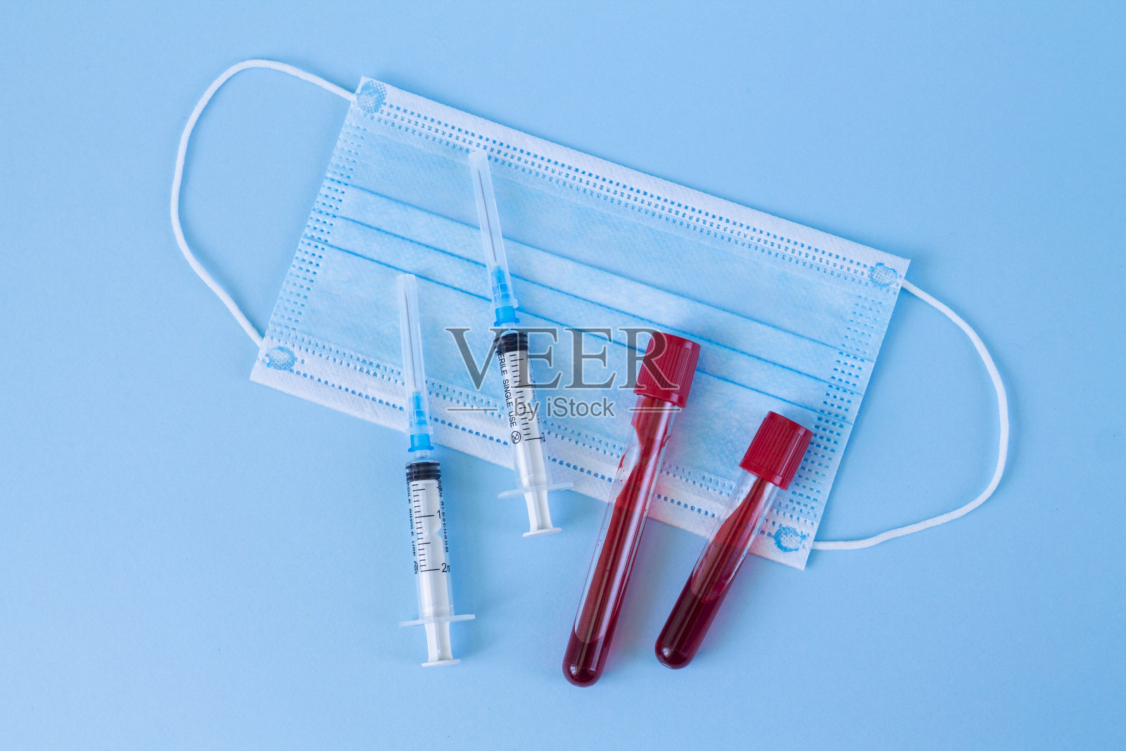 血液试管、抗病毒医用口罩、蓝色背景注射器。健康防护和诊断概念照片摄影图片