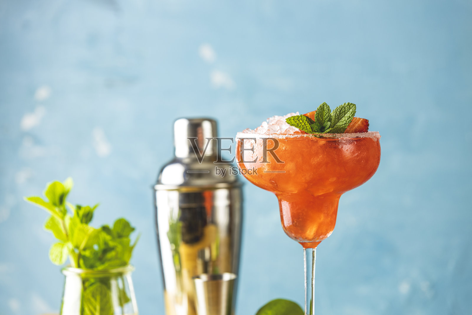 冰冻草莓酸橙薄荷玛格丽塔在高脚玻璃杯靠近与酒吧工具和配料的木桌。高档酒精鲜饮。照片摄影图片